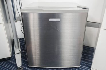 New mini fridge on carpeted floor.