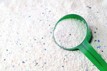 Using a powder laundry detergent to wash the clothes.