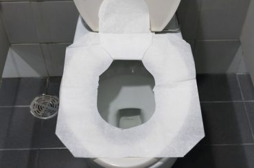 Putting on a toilet seat cover.