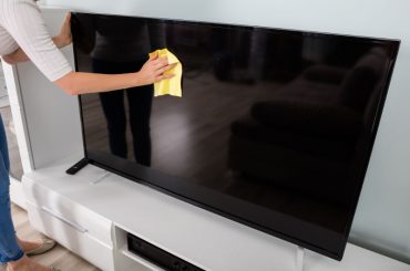 Cleaning a flat screen TV with a microfiber cloth.