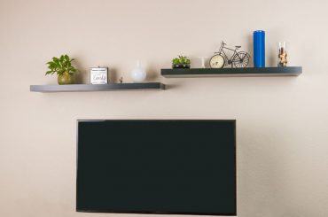 Two floating shelves and a TV installed on a wall.