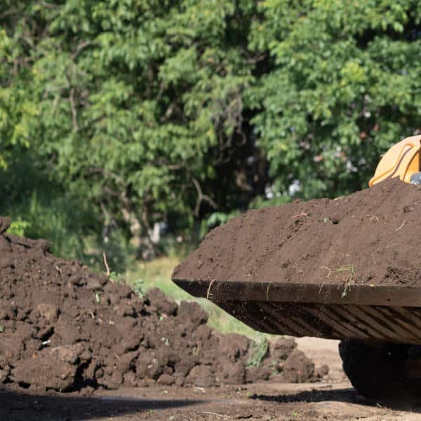 A construction vehicle forming an earth berm designed to block traffic noise and reduce sound transmission.