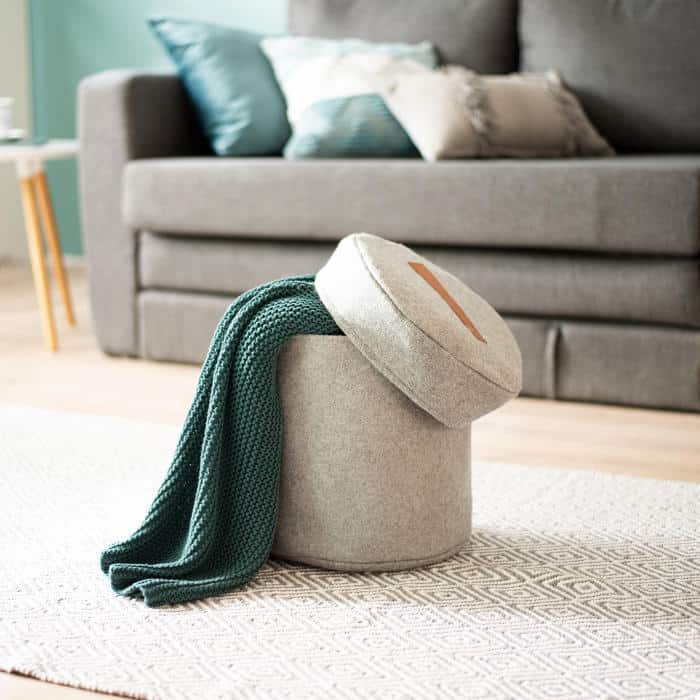 A storage ottoman opened to reveal blankets inside, combining seating and hidden storage in a small living space.