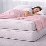 Young woman sleeping on two mattresses that are stacked one on top of the other.
