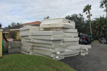Different types of mattresses stored stacked outside.