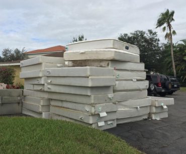 Different types of mattresses stored stacked outside.