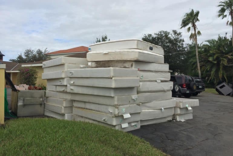 Different types of mattresses stored stacked outside.