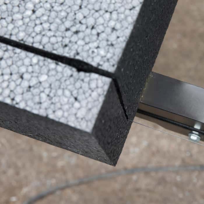 Expanded polystyrene (EPS) insulation being precisely cut using a hot wire cutter for smooth, clean edges.