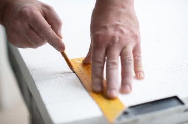 Measuring and marking EPS polystyrene foam to ensure accurate cutting and proper fit during installation.