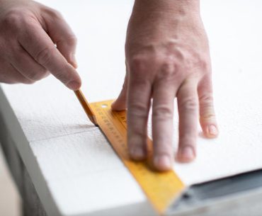 Measuring and marking EPS polystyrene foam to ensure accurate cutting and proper fit during installation.